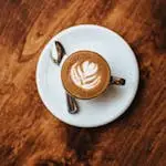A top-down view of cappuccino with latte art, placed on a rustic wooden table.
