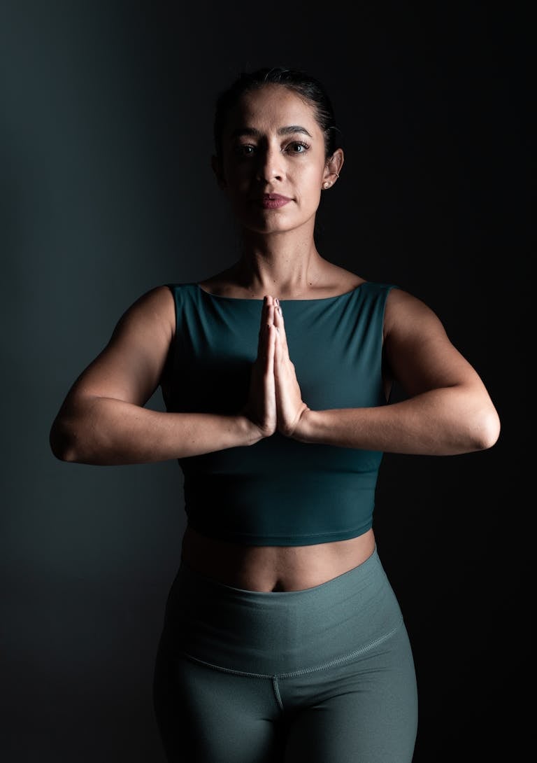 A woman in a yoga pose with hands in namaste, emphasizing inner peace and strength.