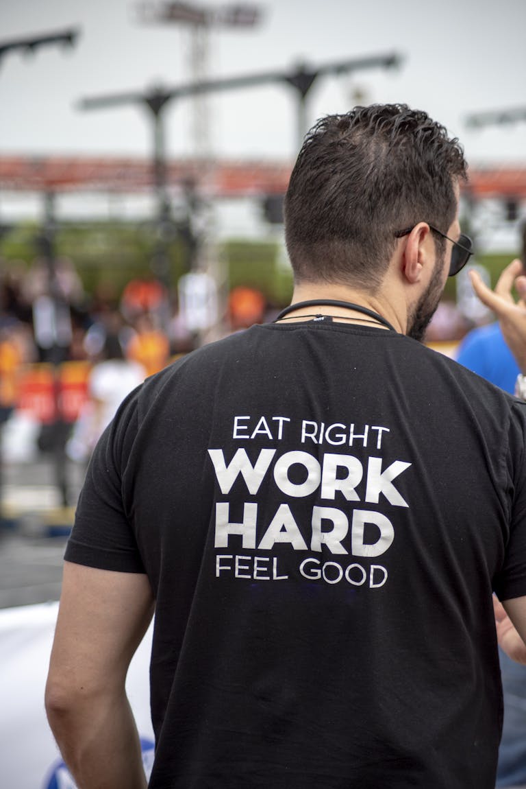 Back view of a man wearing a motivational t-shirt at an outdoor gathering.