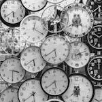 A black and white image displaying a diverse array of vintage wall clocks.
