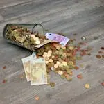 A glass jar with euro coins and banknotes spilled on a wooden surface, representing finance and savings.