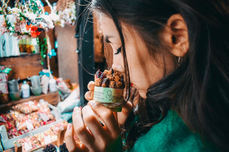 A woman savoring the scent of potpourri at a vibrant London market, capturing the essence of street life.