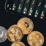 Close-up view of various cryptocurrency coins with a digital market display in the background.