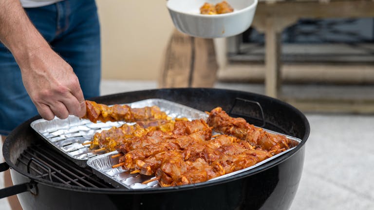 Delicious meat skewers grilling at outdoor barbecue event. Perfect for summer parties.