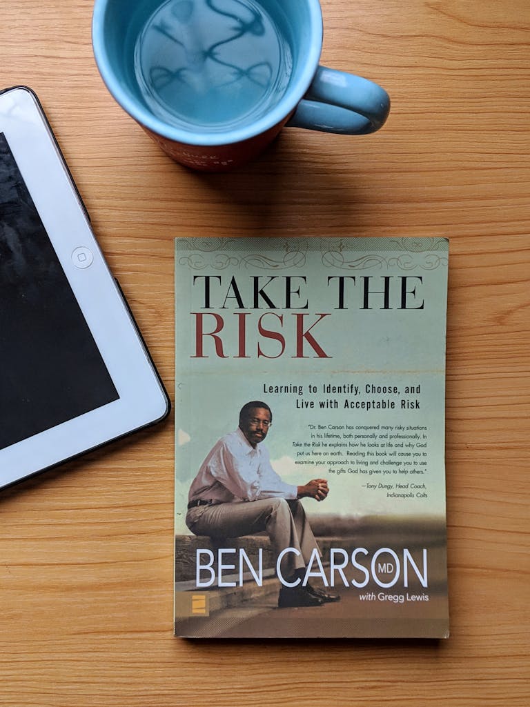 Top view of a Ben Carson book, tablet, and coffee mug on a wooden table.