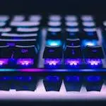A detailed close-up of illuminated mechanical keyboard keys with focus on blue and purple lights.