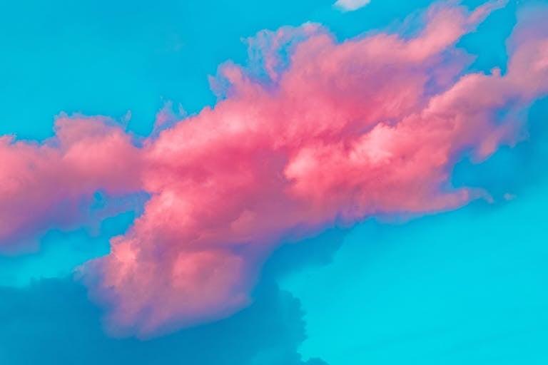 A vibrant pink cloud against a bright blue sky, showcasing a dreamy and creative cloudscape.