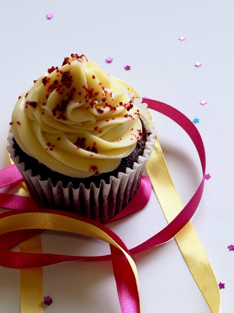 Tempting chocolate cupcake with creamy icing, adorned with colorful ribbons and confetti for a festive celebration.