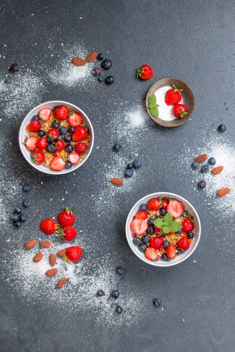Top view of delicious mixed berry and almond bowls on slate, dusted with sugar for a fresh, healthy snack.